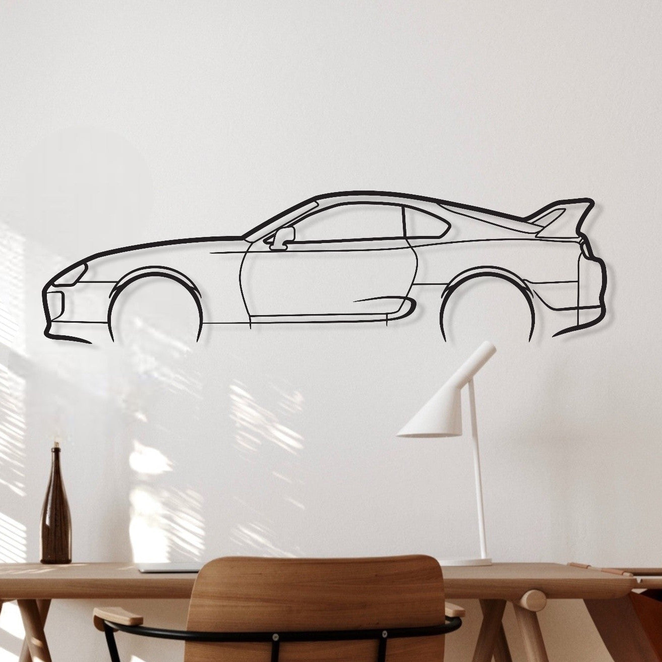Wooden desk with chair against a white wall with a car outline.