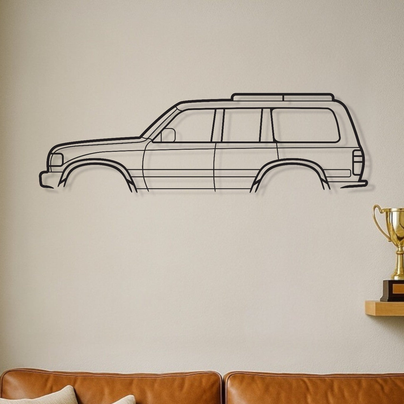 Brown leather sofa with decorative pillows in a room with a wall decal of a car and trophies on a shelf.