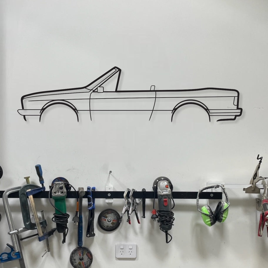 Wall-mounted tool rack with various tools and a car outline on the wall.