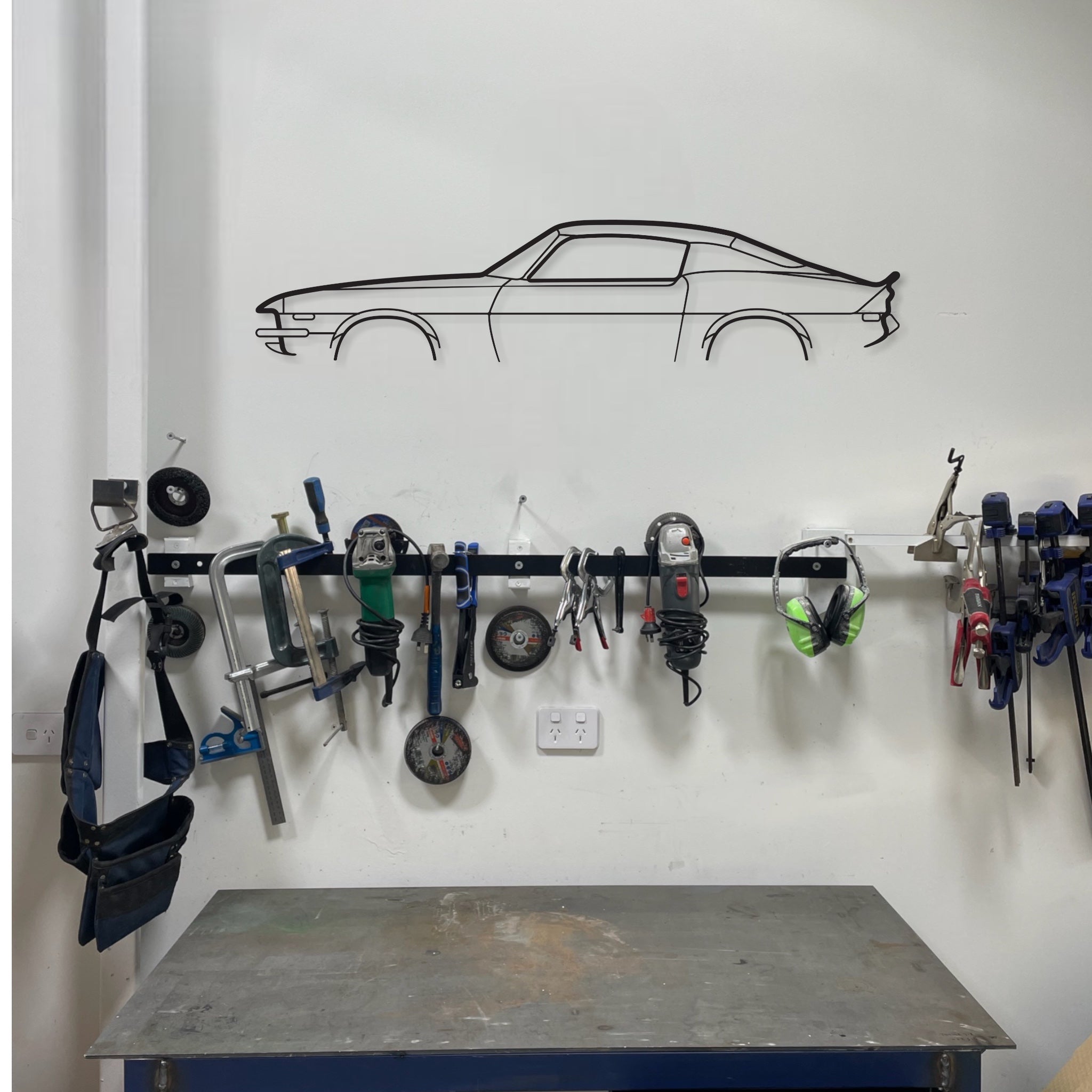 Chevrolet Camaro auto art wall hanging in a garage above a work bench and tools.