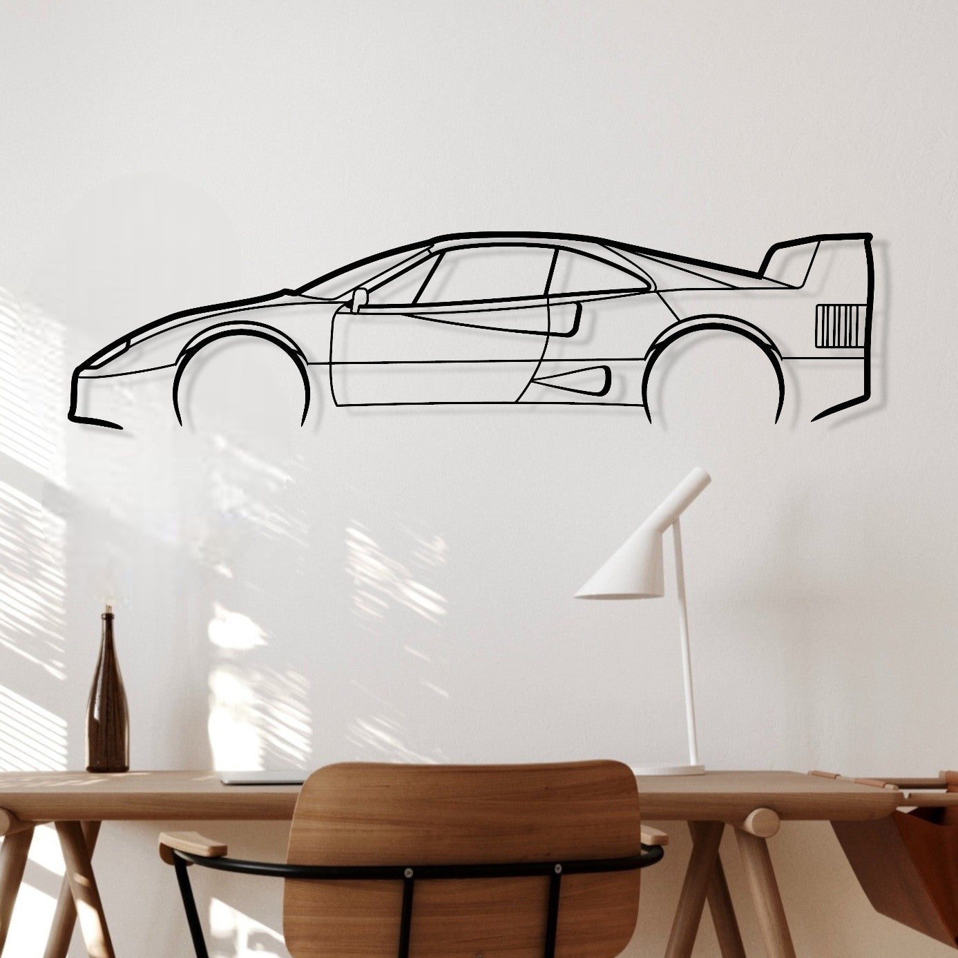 Modern office setup with wooden desk and chair, wall decal of a car, and lamp.