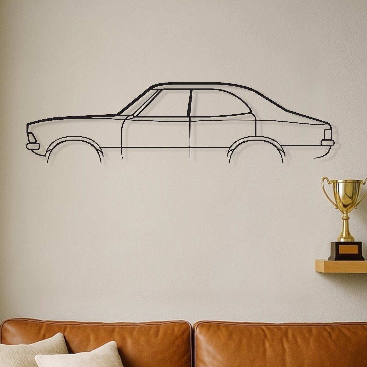 Brown leather sofa with decorative pillows against a wall with a car outline and trophies on a shelf.