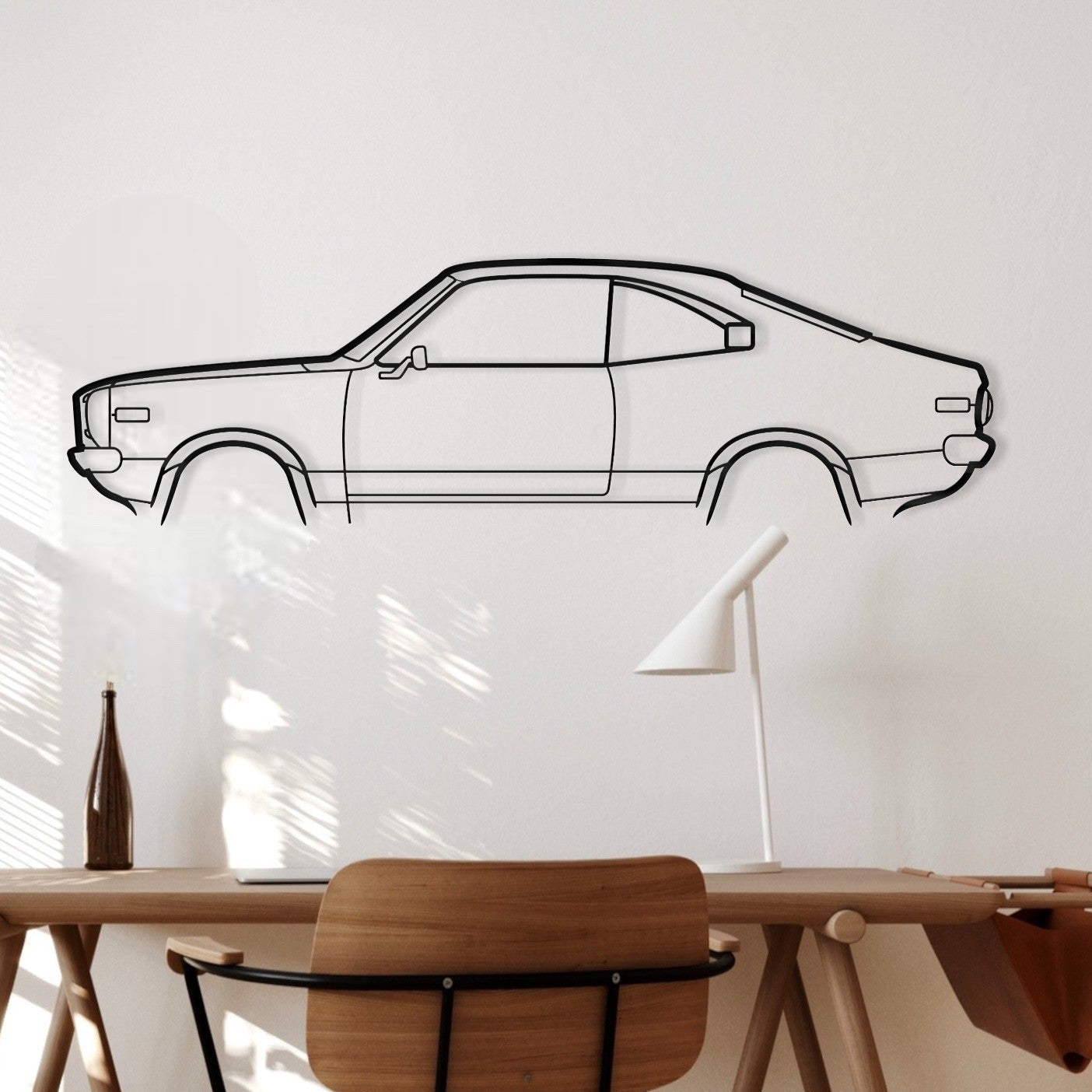 Wooden desk with chair against a white wall with a car outline.