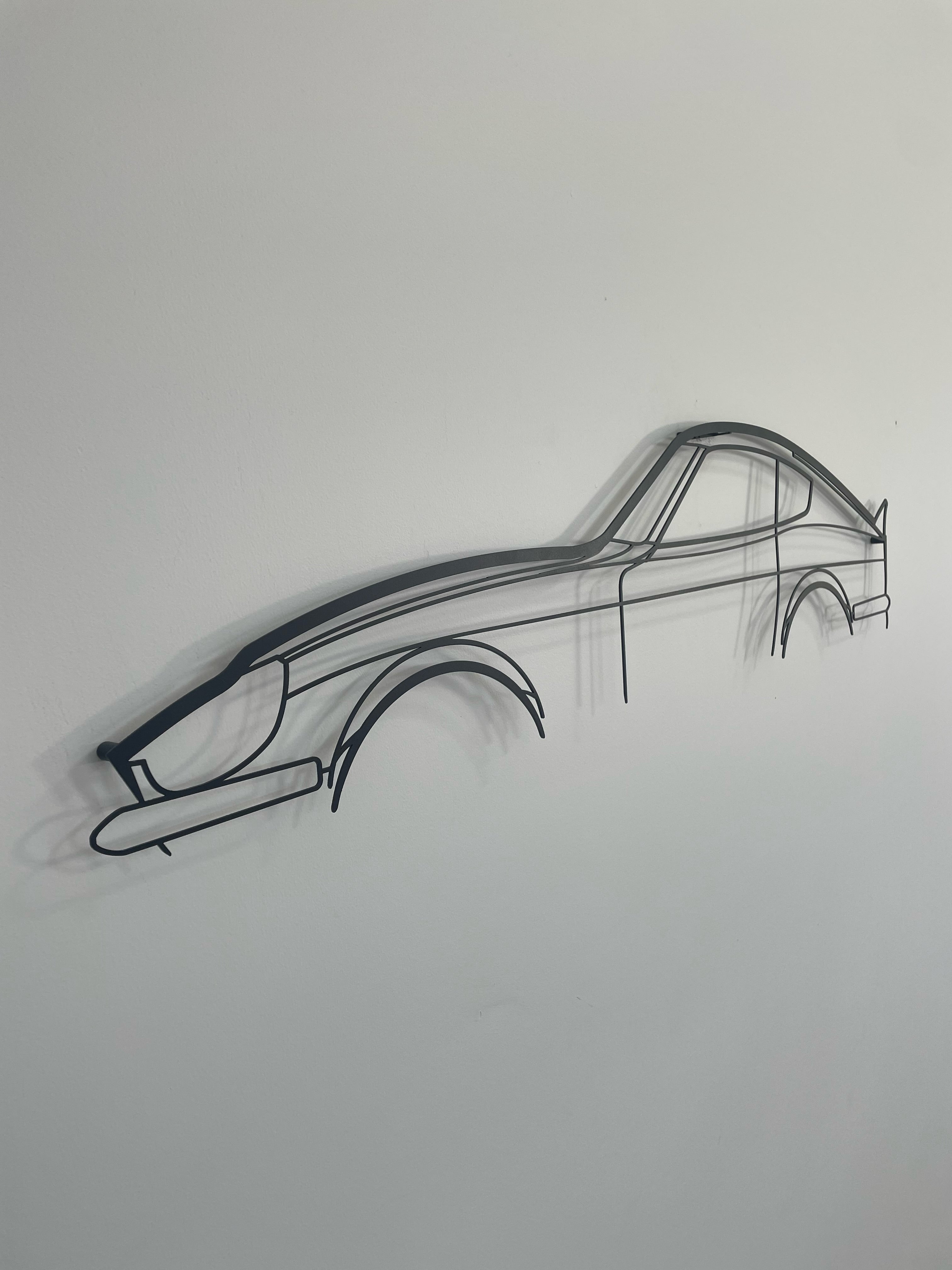 Nissan 240z side-on against a white wall.