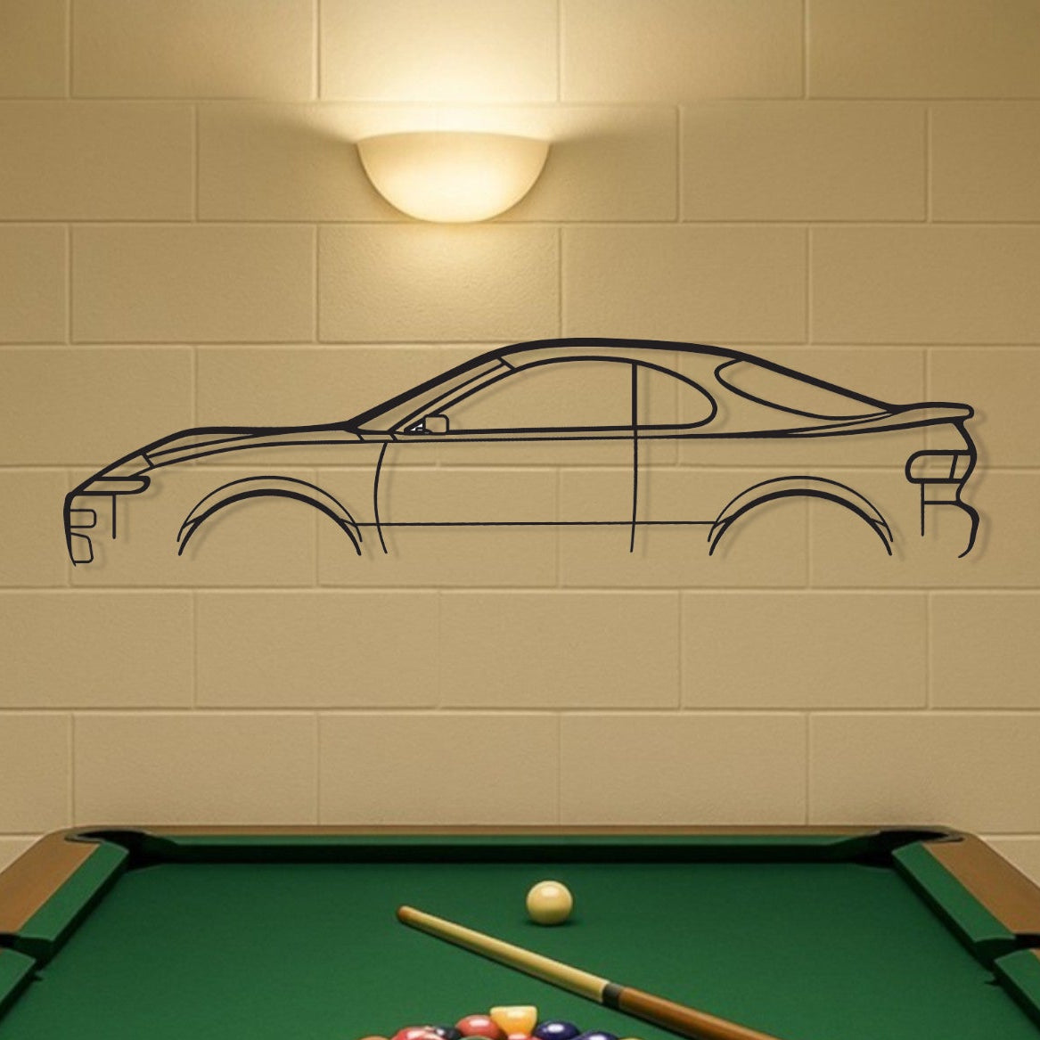 Pool table with billiard balls and cues in a room with a car wall decal.