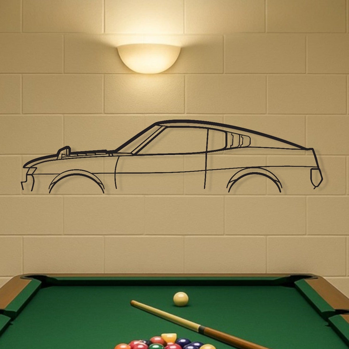 Pool table with billiard balls and cues in a room with a car drawing on the wall.