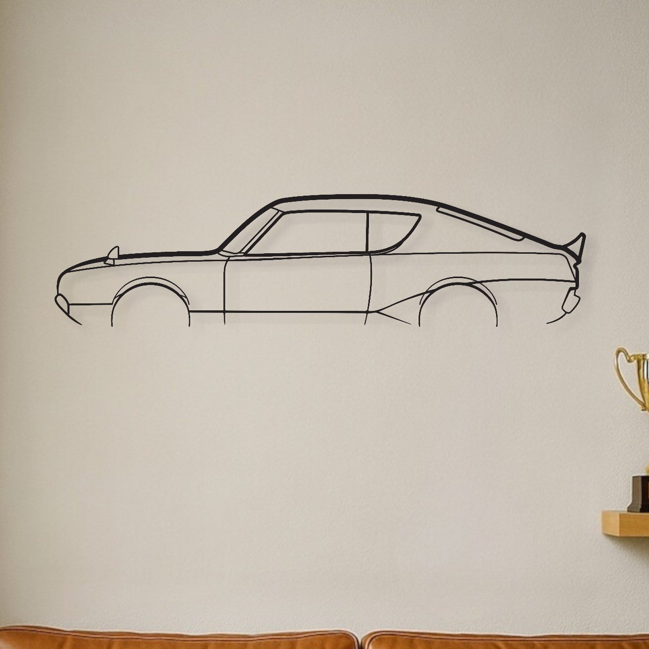 Brown leather sofa with decorative pillows, wall decal of a car, and trophies on a shelf.