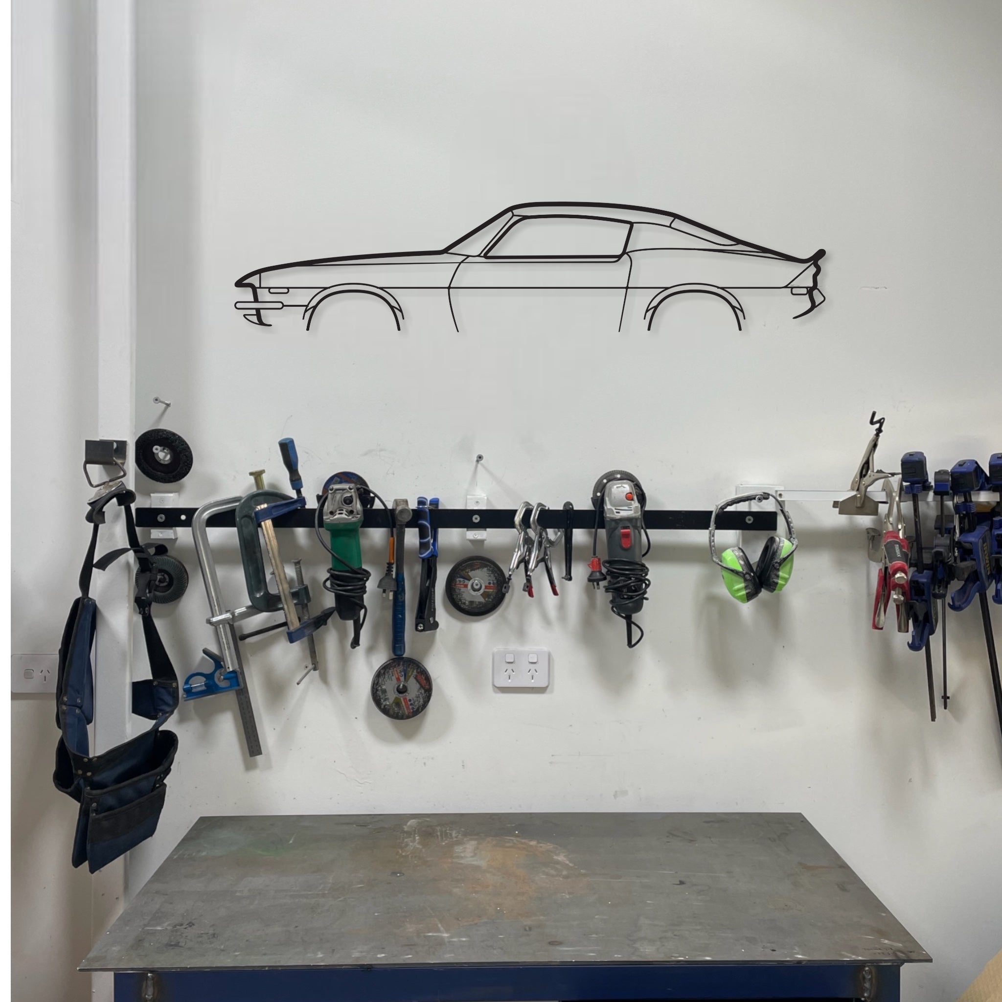 Chevrolet Camaro auto art wall hanging in a garage above a work bench and tools. 