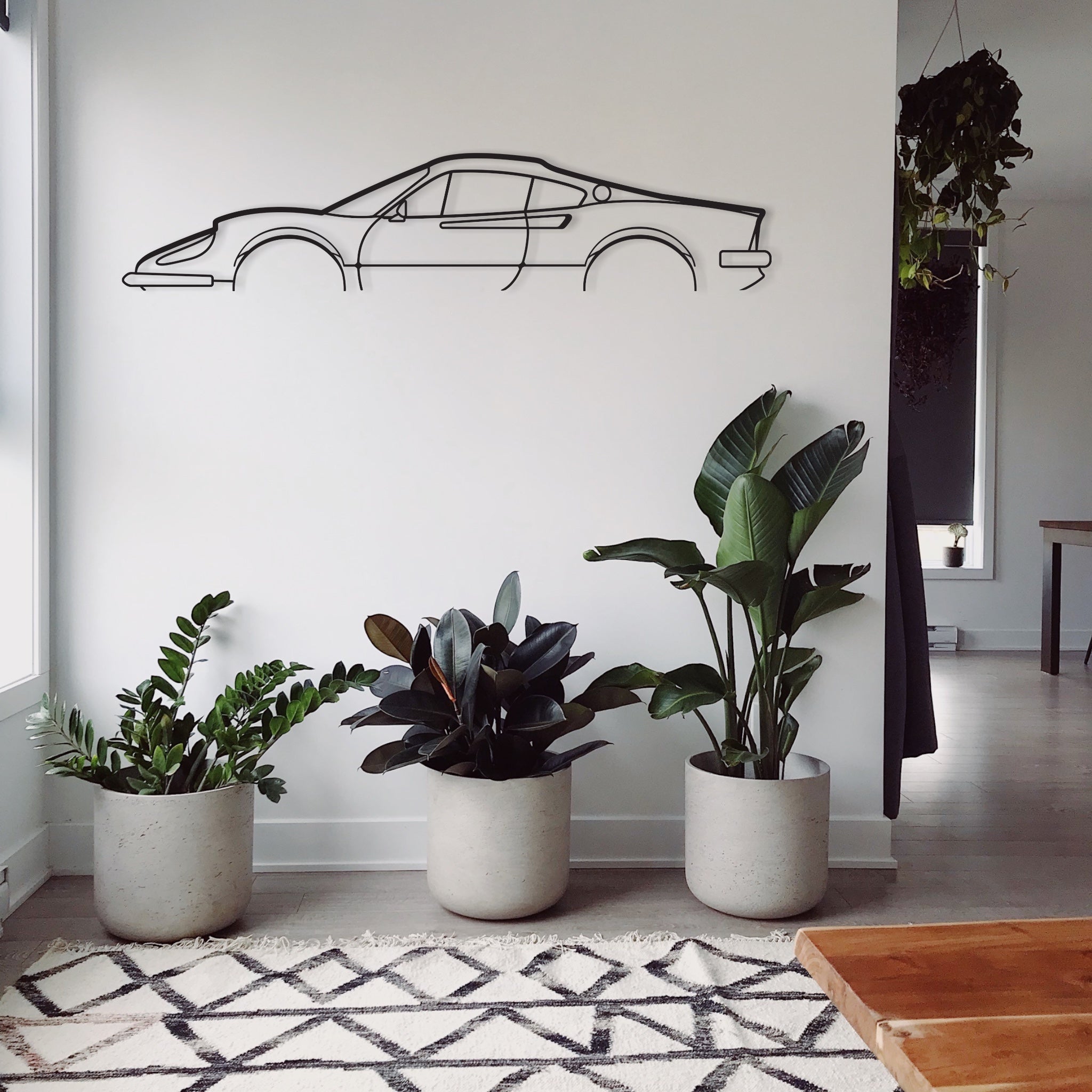 The Ferrari Dino 246 GT car art piece in a lounge room surrounded with greenery. 