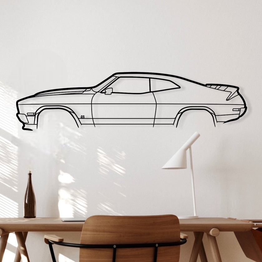 Metal silhouette of a Ford Falcon XC Cobra car hanging on a white wall above a desk and chair.