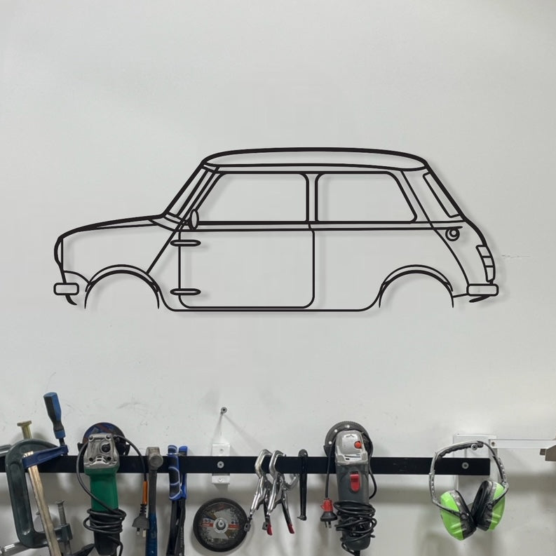 A wall-mounted silhouette of a Mini Cooper car made from metal, displayed above a workbench in a garage setting, with various tools and equipment organized on the wall.