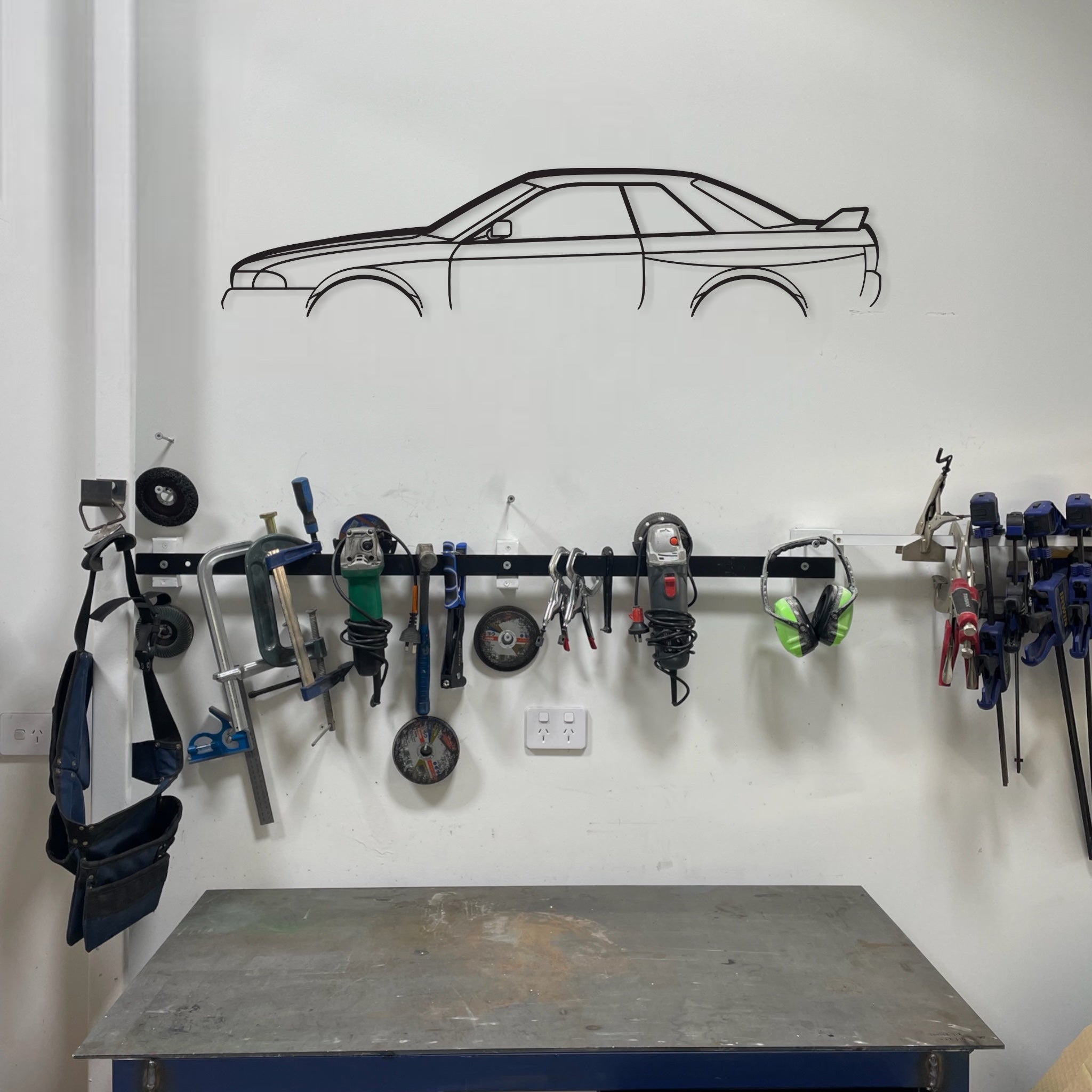 Nissan Skyline R32 GTR car metal stencil wall art piece in a garage.