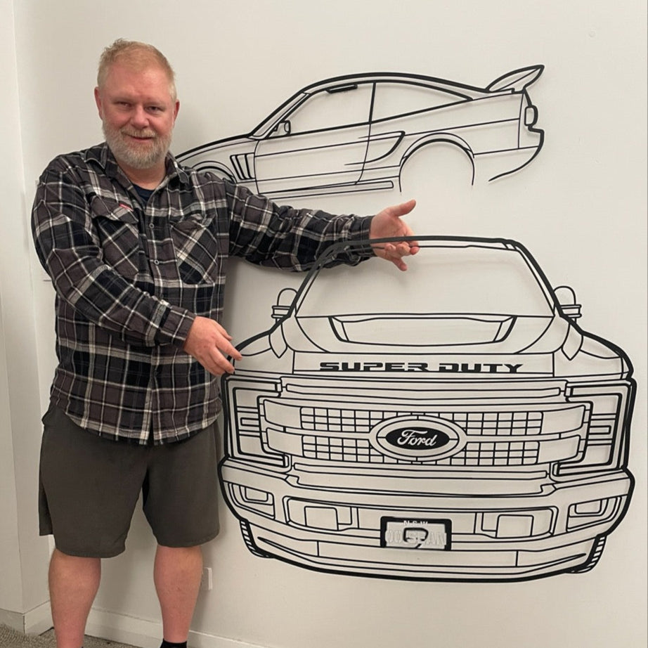 Man standing next to a large outline of a Ford Super Duty truck on a wall.