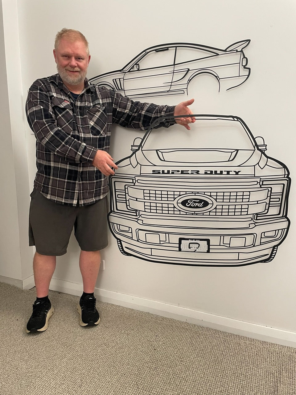 Man standing next to a large outline of a Ford Super Duty truck on a wall.