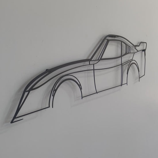 Close up video of a black Toyota Celica LB silhouette wall art piece hanging on a white wall.  