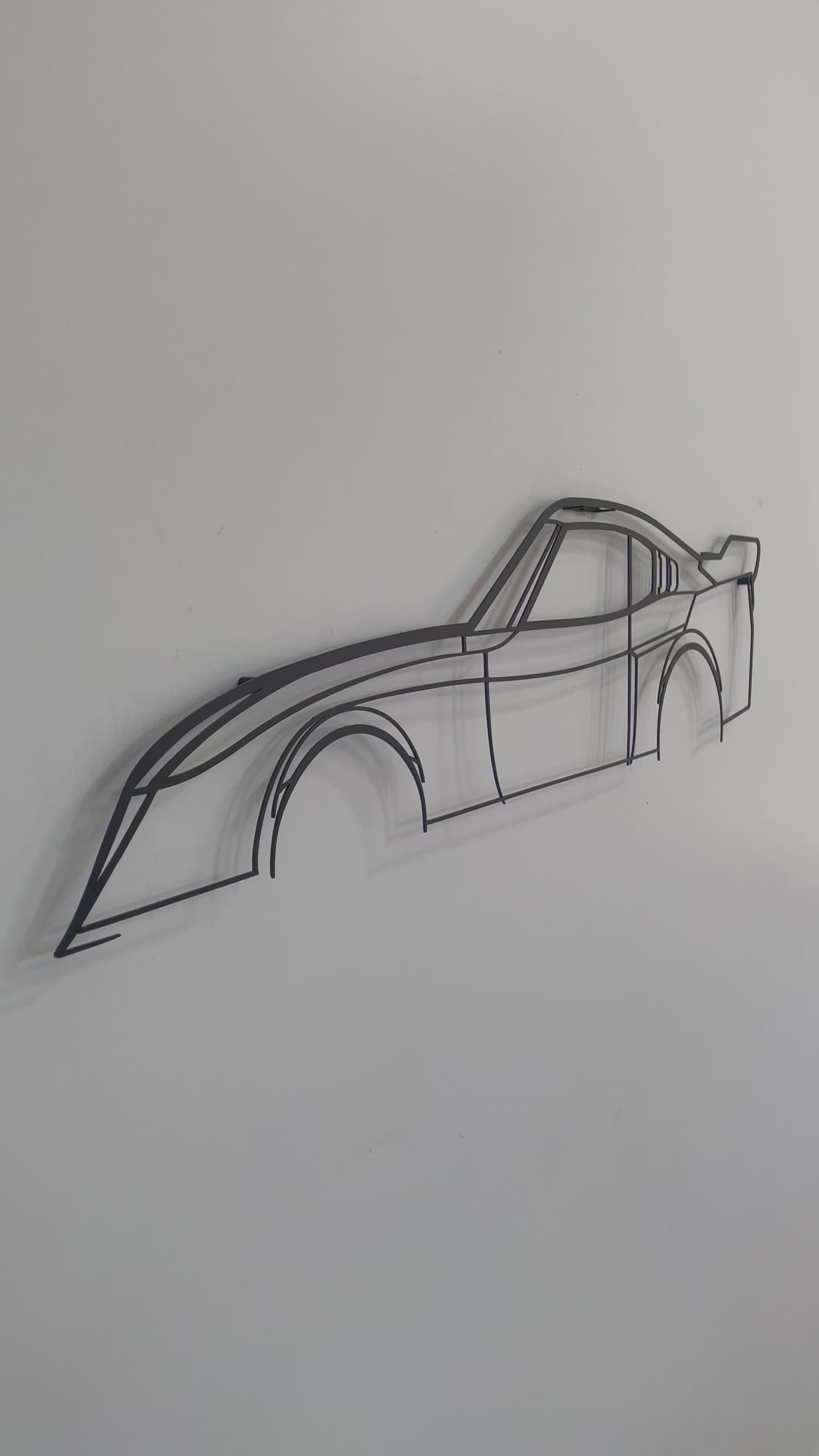 Close up video of a black Toyota Celica LB silhouette wall art piece hanging on a white wall.  